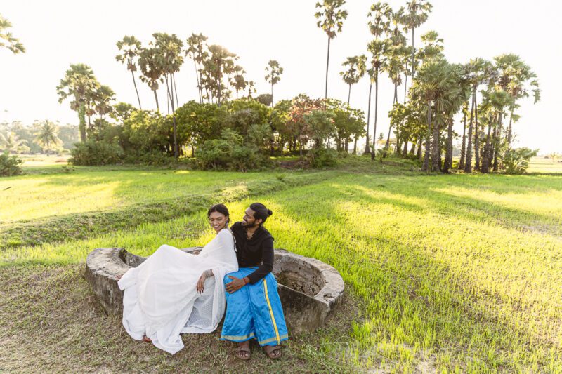 Bride and groom Kobe and Ramya walking hand in hand at Jaffna Fort, with the historic stone walls and ocean backdrop. Romantic post-wedding shoot by Banu Photography.