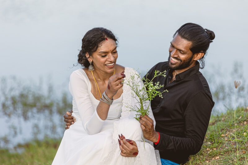 Bride and groom Kobe and Ramya walking hand in hand at Jaffna Fort, with the historic stone walls and ocean backdrop. Romantic post-wedding shoot by Banu Photography.