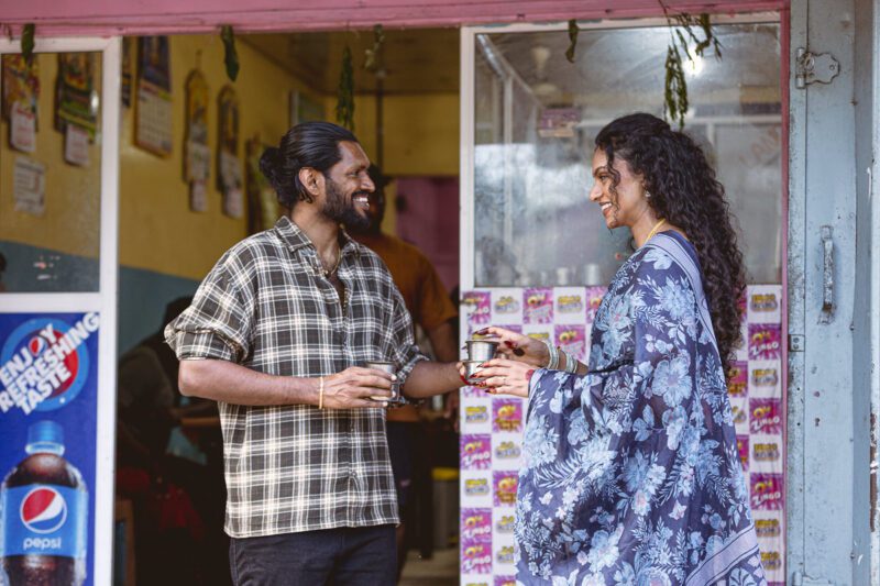 Kobe and Ramya walking through the quiet streets of Jaffna city, surrounded by colonial-style buildings and everyday life. A candid post-wedding moment captured by Banu Photography