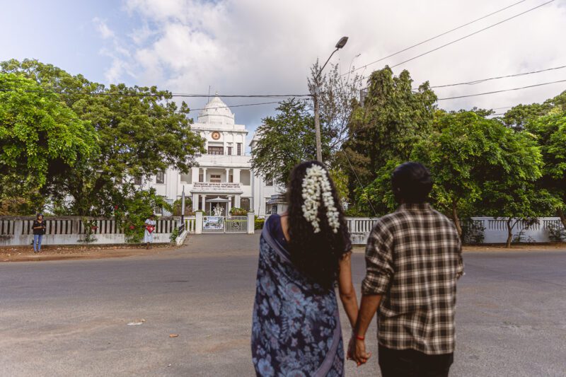 Kobe and Ramya posing in front of the iconic white Jaffna Library, blending elegance and heritage. Wedding portraits captured by Banu Photography.