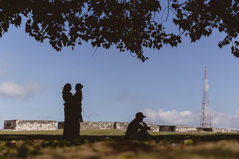 Bride and groom Kobe and Ramya walking hand in hand at Jaffna Fort, with the historic stone walls and ocean backdrop. Romantic post-wedding shoot by Banu Photography.