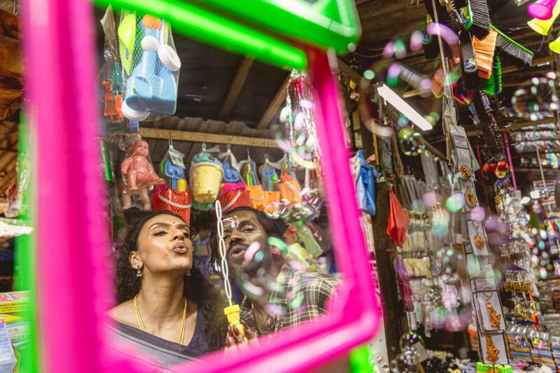 Bride and groom strolling through the vibrant streets near Jaffna Market, filled with bicycles, local shops, and colorful life. Authentic cultural portrait by Banu Photography.